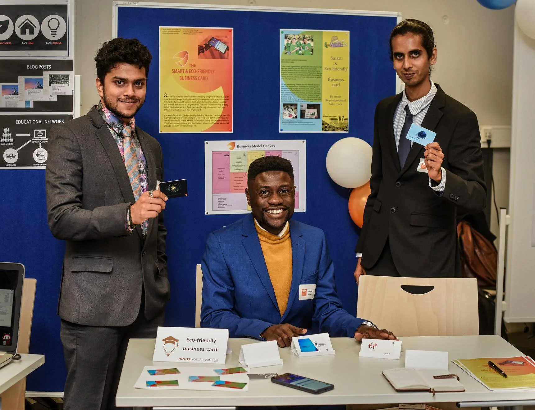 Three members of the Eco-friendly Programmed Business Card team at their Best Idea Cup 2019 exhibition stand, presenting prototype cards and project posters