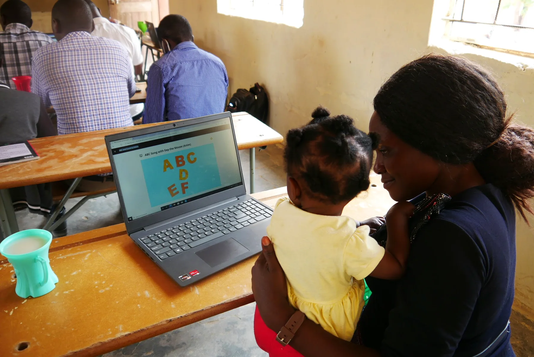 A woman and young child viewing educational content on a laptop in the classroom