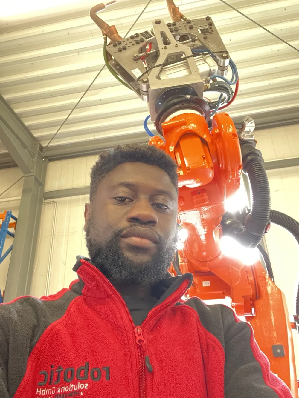 Victor pictured beside an orange ABB industrial robot and its equipment