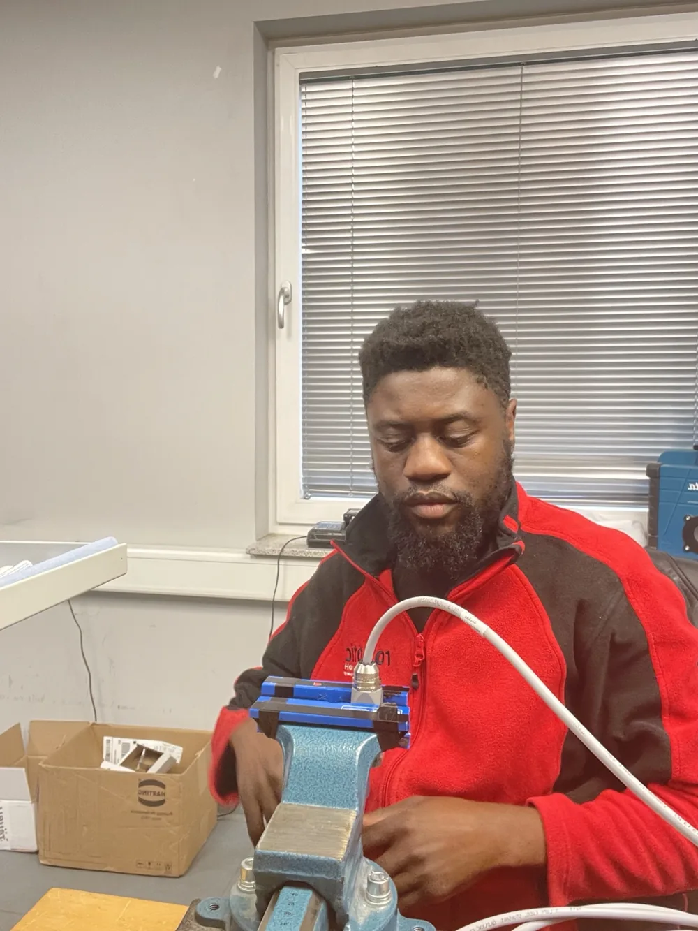 Victor preparing an industrial cable or hose assembly secured in a workbench vise